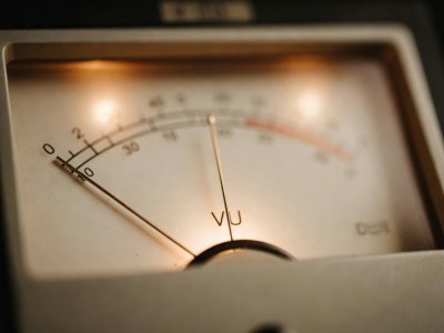 Close-up of a warm backlit analog decibel meter needle hovering near zero VU