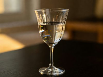 Close-up of a thin crystal goblet half-filled with water catching warm sidelight